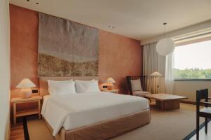 a bedroom with a large white bed and a chair at Lopota Lake Resort & Spa in Napareuli