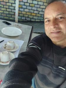 a man sitting at a table with a cup and saucer at Pousada Vale das Águas foz in Foz do Iguaçu