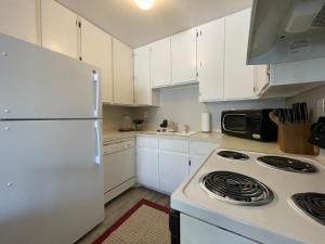 a kitchen with white cabinets and a white refrigerator at Campus West Nest - King Bed, Walk to CSU in Fort Collins
