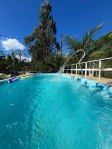 a large blue swimming pool with a water fountain at Pousada Hostels Foryou in Ibiraçu