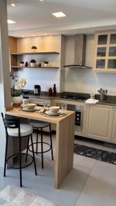 a kitchen with a table with chairs and a stove at Excelente Loft no Quartier in Pelotas