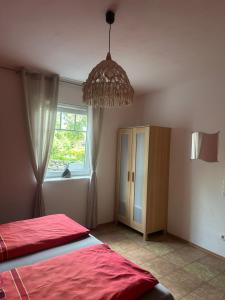 a bedroom with a red bed and a chandelier at Ferienwohnung am Nurburgring in Welcherath