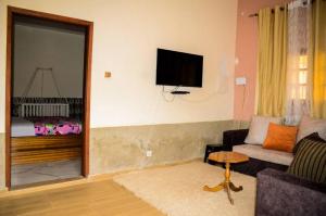 a living room with a couch and a tv on the wall at Havre de paix in Saint-Louis