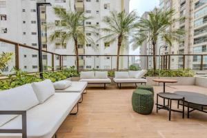 a rooftop patio with white couches and tables and palm trees at Refúgio Moderno no Campo Belo NOVO in Sao Paulo