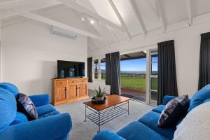a living room with blue couches and a coffee table at The Cottage - Rotorua Holiday Farmstay in Rotorua
