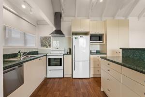 a kitchen with white cabinets and a refrigerator at The Cottage - Rotorua Holiday Farmstay in Rotorua