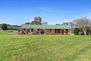 a house with a green roof on a grass field at The Cottage - Rotorua Holiday Farmstay in Rotorua