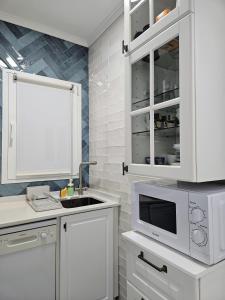 a white kitchen with a sink and a microwave at BlueSea Apartments Bergantin in Torrevieja