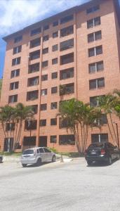 two cars parked in front of a large building at Magnífico Apartamento en Mérida in Mérida