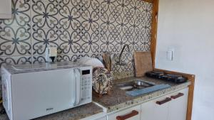 a kitchen with a microwave and a sink at Suíte Coqueiros Paraty in Paraty