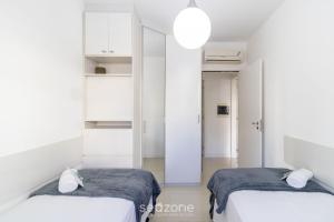 two beds in a room with white walls at Apto c/ Churrasqueira em Cond. c/ Piscina BRI0102 in Florianópolis +21 photos