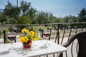 two glasses of wine and a vase of flowers on a table at Casa Angelina 2 in Laganas