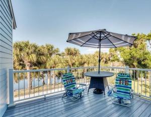 a table with two chairs and an umbrella on a deck at Luxury Home with Deeded Private Beach Access Sanibel Island - 28 Day Stay Minumum in Sanibel
