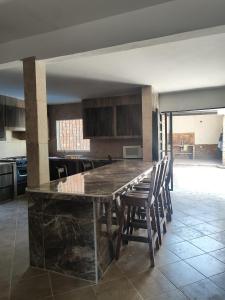 a kitchen with a large counter with chairs around it at Extraordinaria Casa con Piscina in Mérida
