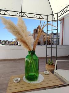a green vase with grass in it on a table at La Casa di Joao in Piazza Armerina