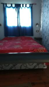 a bedroom with a bed with a red blanket and a window at Complejo Rio Azul in La Porteña