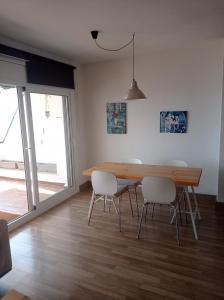 a dining room with a wooden table and white chairs at Pis a primera línia de mar in L'Escala +12 photos