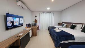 a bedroom with two beds and a flat screen tv at Pousada Loft Marabá in Marabá