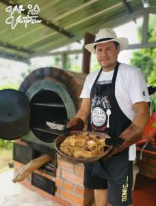 a man holding a plate of food in front of an oven at Villa Victoria Campestre in Rivera