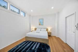 a white bedroom with a bed and a rug at Stylish 4-Bed Townhouse with Panoramic Ocean Views in Brisbane +10 photos