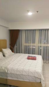 a bedroom with a large white bed in front of a window at Great Deal Apartemen Grand Jati Junction Unit 1811 in Medan
