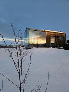 Panorama Glass Lodge WEST في أكرانيس: بيت زجاجي فوق فناء مغطى بالثلوج