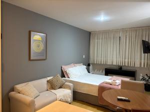 a bedroom with a bed and a couch and a table at SH130 Abrace a Simplicidade na Rua Bela Cintra in Sao Paulo