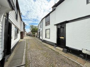 an alley with two white buildings and a cobblestone street at One Church Square in Rye