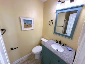a bathroom with a sink and a toilet and a mirror at KH5205- Katmandunes in Kitty Hawk