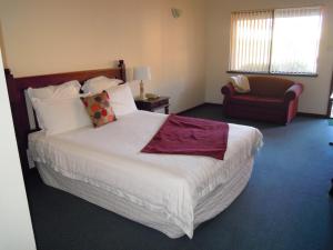 una habitación de hotel con una cama grande y una silla en Tree Top Walk Motel en Walpole