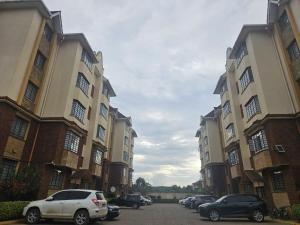 a row of buildings with cars parked in a parking lot at The Monarch Suites in Lanet