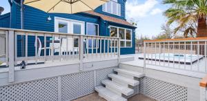 a blue house with a porch with stairs and an umbrella at Scenic 5-Acre Retreat with Hot Tub Pool & Game Room in Manor