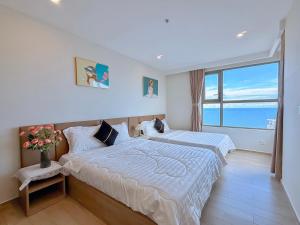 two beds in a room with a large window at The Sóng Apartment Vũng Tàu - Căn Hộ Hồ Bơi-Olive Homestay in Vung Tau +230 photos