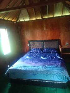 a bed with a blue comforter in a room at New Rinjani Homestay in Tetebatu