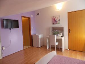a living room with a table and a tv on the wall at Apartments and Rooms Jasna in Hvar