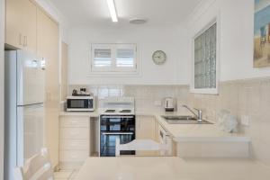 Absolute Beachfront Apartment 1T في لينوكس هيد: مطبخ أبيض مع حوض وميكروويف +18 صورة