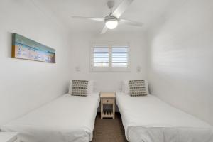 Absolute Beachfront Apartment 1T في لينوكس هيد: سريرين توأم في غرفة بها نافذة