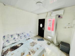 a white bedroom with a bed and a window at Costa Homestay in Dili