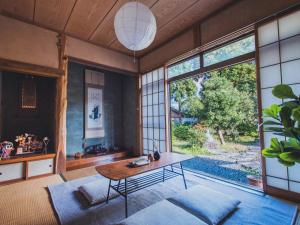 a living room with a table and a large window at 最大8名 庭園に住むアート Active Art Hotel 80畳の広さを誇る古民家 日本庭園を独り占め in Sado +93 photos