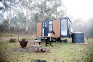 Doyles CreekBundaleer Tiny House 2 by Tiny Away的坐在田野拖车上的一个小房子