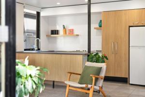 a kitchen with a chair and a refrigerator at The Hastings Beach Houses in Noosa Heads
