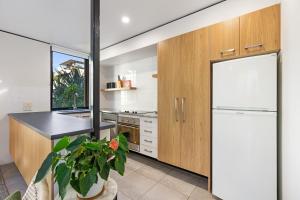 a kitchen with wooden cabinets and a white refrigerator at The Hastings Beach Houses in Noosa Heads