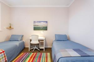 a bedroom with two beds and a desk with a chair at Living the Dream - 3 bedroom House South Fremantle in South Fremantle
