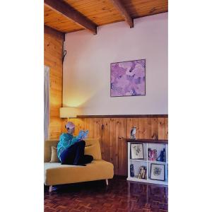 a woman sitting on a couch reading a book at Blue Wren Mews in Halls Gap