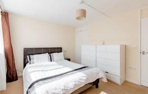 Private Beautiful Cozy Double Bedroom in London في South Norwood: غرفة نوم بيضاء مع سرير كبير وخزانة بيضاء
