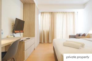 a hotel room with two beds and a desk with a tv at Warm Aston Bellevue HOTEL Apartment - SMART TV in Jakarta