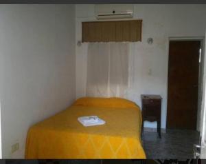 a bedroom with a bed with a yellow blanket at Hotel Carboni in Larroque