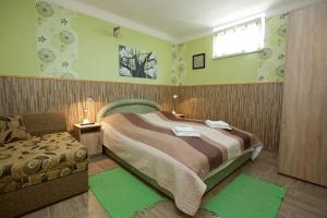 a bedroom with a large bed and a chair at Főnix Apartmanház in Hajdúszoboszló