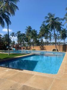 a large swimming pool with palm trees in the background at Villa Vacacional Los Cayos in Boca de Aroa