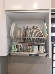 a shelf filled with plates and dishes in a kitchen at Azzahra Homestay in Permatang Pauh